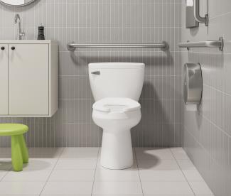 Interior of a modern medical restroom featuring a pressure-assisted toilet and ADA grab bars.
