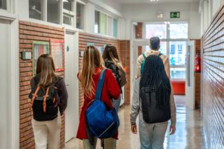 Kids wearing backpacks walking down a hallway in a school